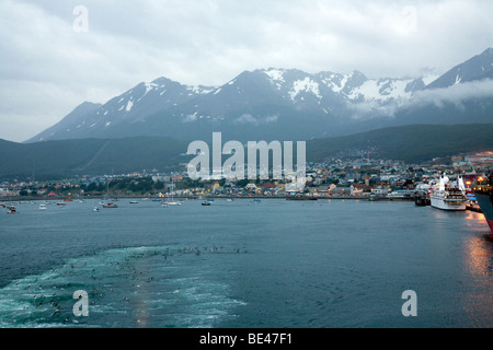 Antarctica bound expedition ship leaving Ushuaia, with seabirds feeding in its wake. Le Diamant is in view on the right hand sid Stock Photo