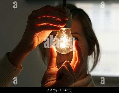YOUNG WOMAN SCREWING A LIGHT BULB Stock Photo - Alamy