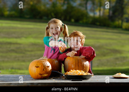 Two children carving pumpkins for Halloween decoration Stock Photo