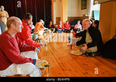 ISKCON Hare Krishna disciples and visitors eat a vegetarian feast in a temple room Stock Photo