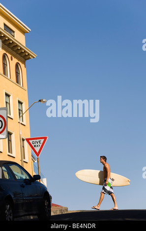 Man carrying surfboard along road at Bondi Beach.  Sydney, New South Wales, AUSTRALIA Stock Photo