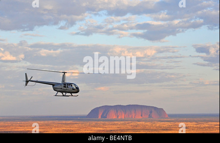 Aerial view of a helicopter in front of Uluru, Ayers Rock at sunset, Uluru-Kata Tjuta National Park, Northern Territory, Austra Stock Photo