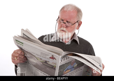 Older man reading newspaper with angry expression. Stock Photo