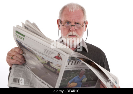 Older man reading newspaper with angry expression. Stock Photo
