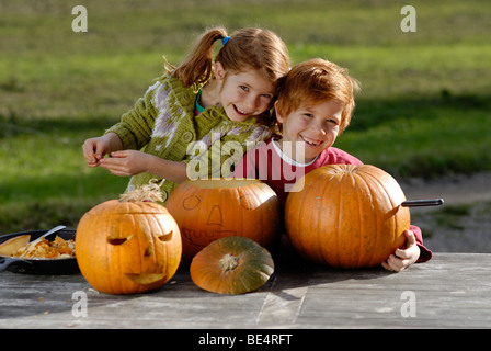 Two children carving pumpkins for Halloween decoration Stock Photo