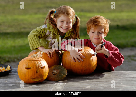 Two children carving pumpkins for Halloween decoration Stock Photo