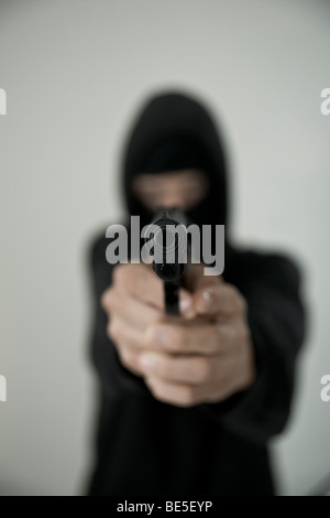 Adolescent wearing black, masked, aiming with a gun Stock Photo