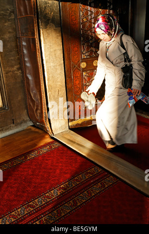 Muslim woman with headscarf exiting a mosque, shoes in hand, Ueskuedar, Istanbul, Turkey Stock Photo