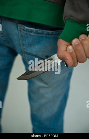 Adolescent, partial view, hiding knife behind his back Stock Photo