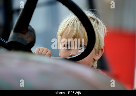 Child blond Boy driving a vintage tractor engine Stock Photo