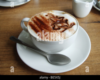 A cup of cappucino with a graphic depiction of a cup of coffee in the froth Stock Photo