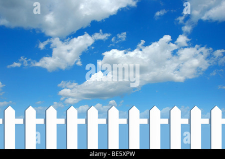White fence in front of blue sky with clouds Stock Photo