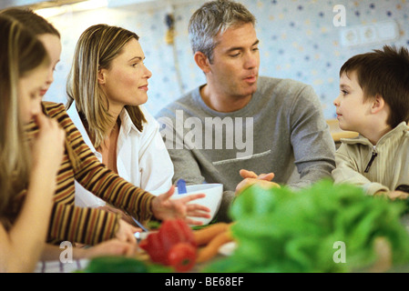 Family together in kitchen, raw vegetables on counter Stock Photo