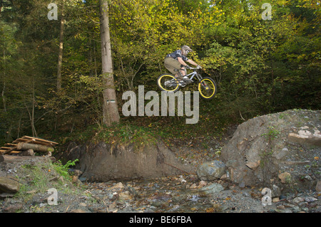 Mountainbiker jumping over a creek on a downhill track at Hopfgarten in the Brixental valley, Tyrol, Austria, Europe Stock Photo
