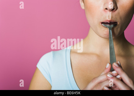 Woman licking spoon, cropped Stock Photo