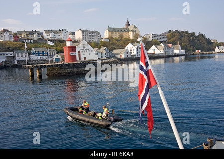 Small rubber boat with crew members travels between cruise ship and dock at the harbor in lesund, Norway. Stock Photo