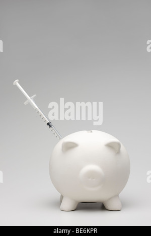 Swine flu concept with syringe inserted into piggy bank Stock Photo