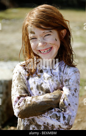 Child totally covered in mud, dirty, wild, untypical girl Stock Photo