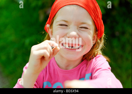 Little girl with a tooth gap, top incisor teeth are missing, happily smiling over the lost tooth for the tooth fairy