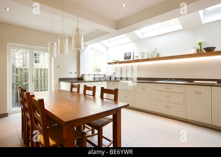Kitchen side extension London terrace Oak table skylights Velux feature green wall Stock Photo