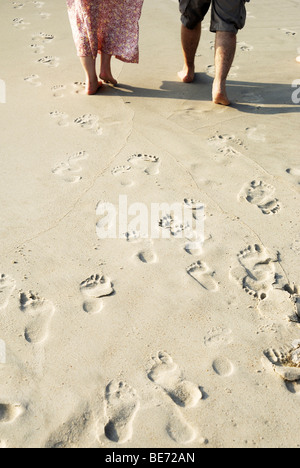 Footprints and couple on the beach Stock Photo