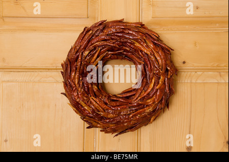 dried red chilli peppers hanging on wooden door Stock Photo