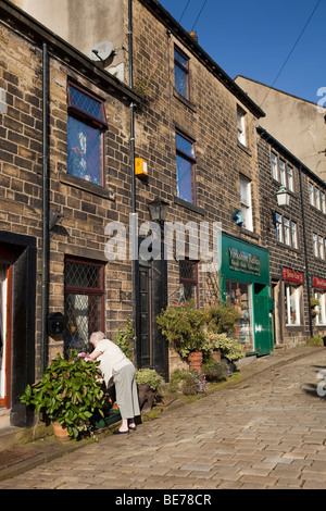 UK, England, Yorkshire, Haworth, Main Street, woman tending window box of former weavers cottage Stock Photo