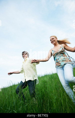 Young couple in love, holding hands while running in a meadow Stock Photo