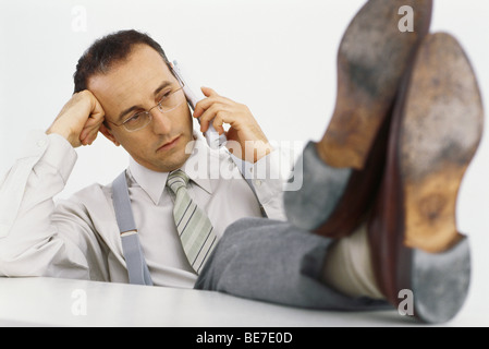 Businessman on phone call with feet up on desk Stock Photo