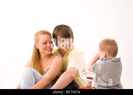 Young couple with their son on the Bobbycar, laughing Stock Photo