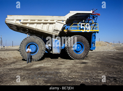 man in front of huge wheel of mining dump truck - uranium mine of rossing - namibia Stock Photo