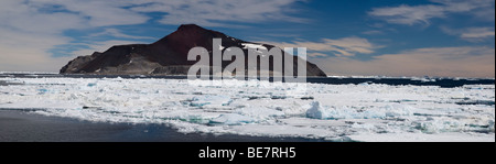 Remote volcano Paulet island Antarctica surrounded by ice floe tall volcanic mountain, blue sky background with fluffy white clouds panoramic view Stock Photo