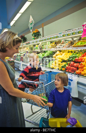 Shopping for families grocery needs in fresh produce department of up scale supermarket. Children Stock Photo