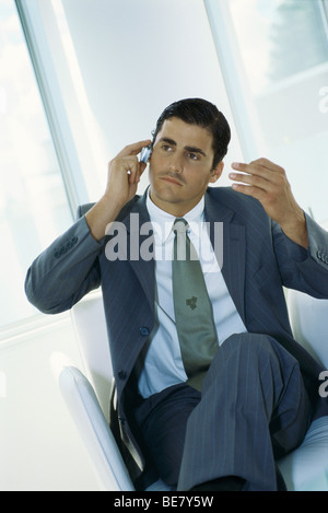 Businessman sitting with legs crossed, using cell phone Stock Photo