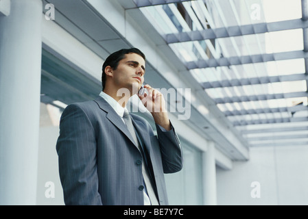 Businessman standing outside office building using cell phone Stock Photo