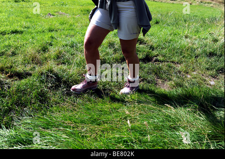 Female walker wearing pink Timberland boots in muddy field Lake District Cumbria UK Stock Photo