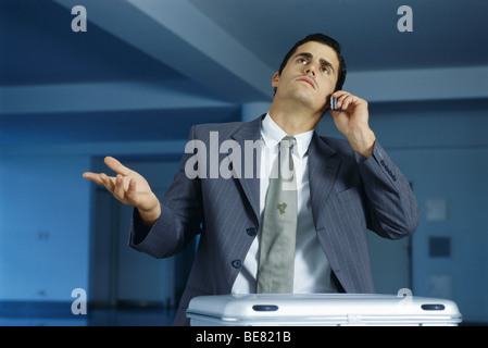 Businessman talking on cell phone, making frustrated gesture with hand Stock Photo