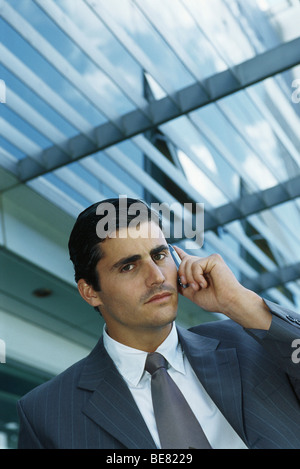Businessman standing outside office building using cell phone Stock Photo