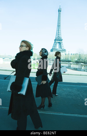 Three women walking, all dressed in black and carrying laptop computers, Eiffel Tower in background Stock Photo
