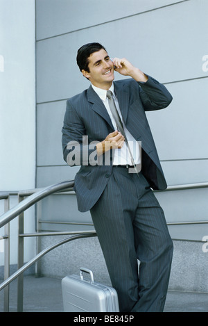 Businessman using cell phone, leaning against railing Stock Photo