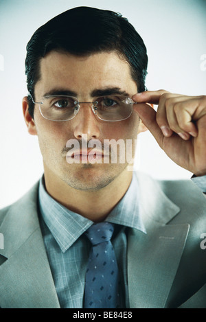 Businessman looking at camera, adjusting glasses, portrait Stock Photo