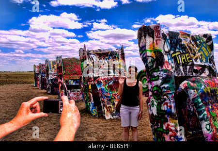 Tourist taking picture with camera at the Cadillac Ranch with buried cars in ground in Amarillo Texas USA Stock Photo