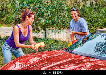 Affluent young Couple in their 30s having fun washing red car  Stock Photo