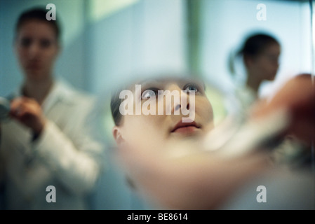 Woman putting on makeup, close-up of reflection in powder compact mirror Stock Photo