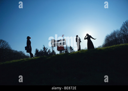 Three females and desk in field, two talking on landline phone, silhouette, low angle view Stock Photo