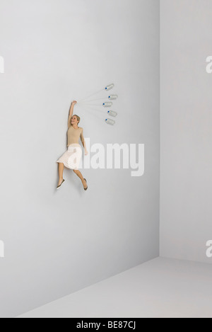 Woman held aloft by bunch of water bottles Stock Photo
