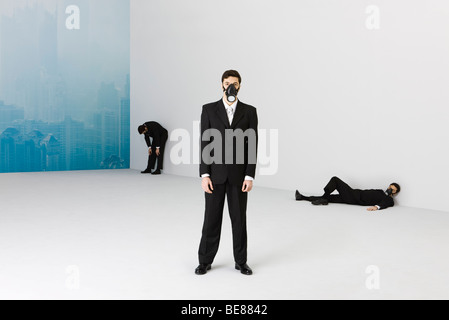 Businessmen wearing gas mask, cityscape obscured by smog in background Stock Photo