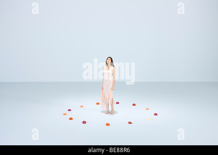 Young woman standing within circle of flowers, looking up Stock Photo