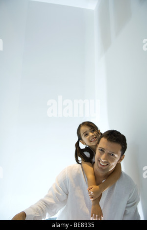 Little girl with arms around father's neck, both smiling Stock Photo