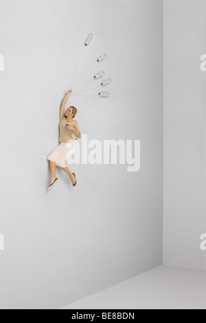 Woman held aloft by bunch of water bottles Stock Photo